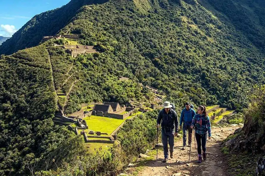 Hikers walking along the mountain trail with a full view of Choquequirao citadel during the 3-day Choquequirao Cusco Trek.
